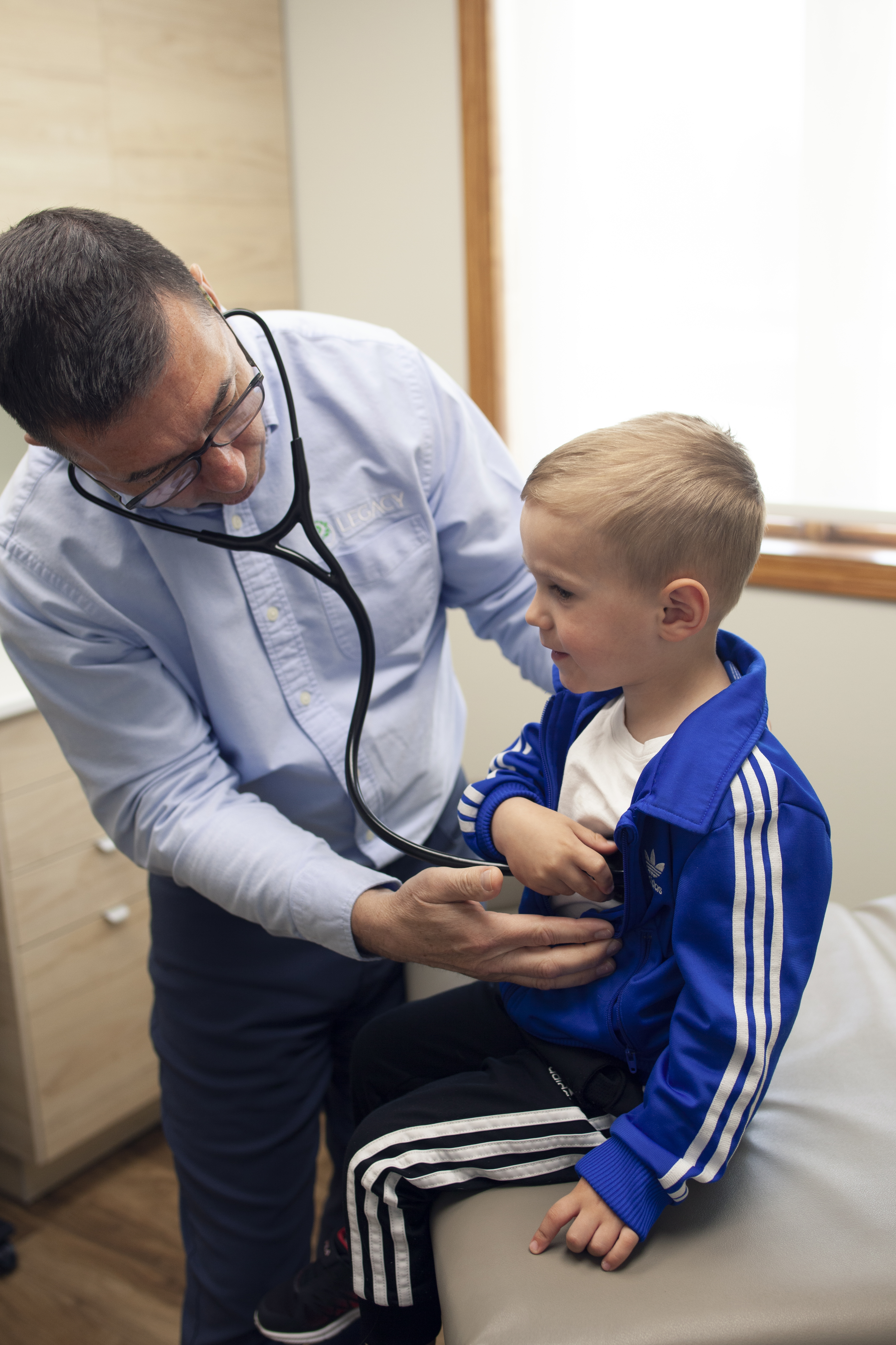 Dr. Eric Miller examining a young patient with a stethoscope